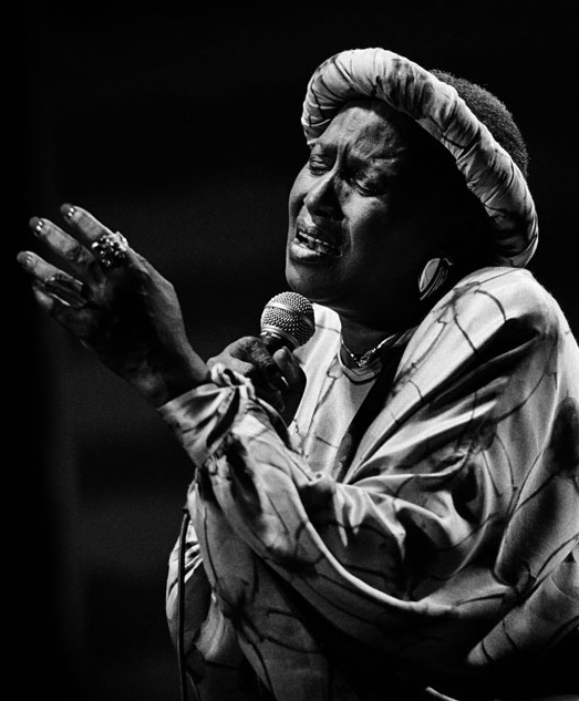 Black and white image of musician and Black rights activist Miriam Makeba singing on stage.