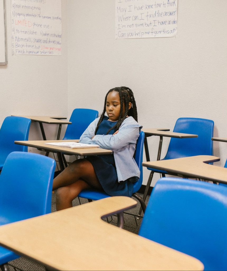 Young girl sitting along in classroom looking sad