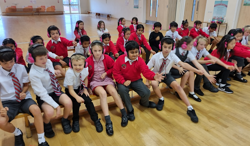 Cheam Academy Trust students sit on a wooden bench in a school hall, enjoying using Now Press Play.