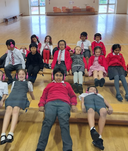 Cheam Academy Trust students lie on wooden benches in a school hall, using Now Press Play. They look shocked and excitable.