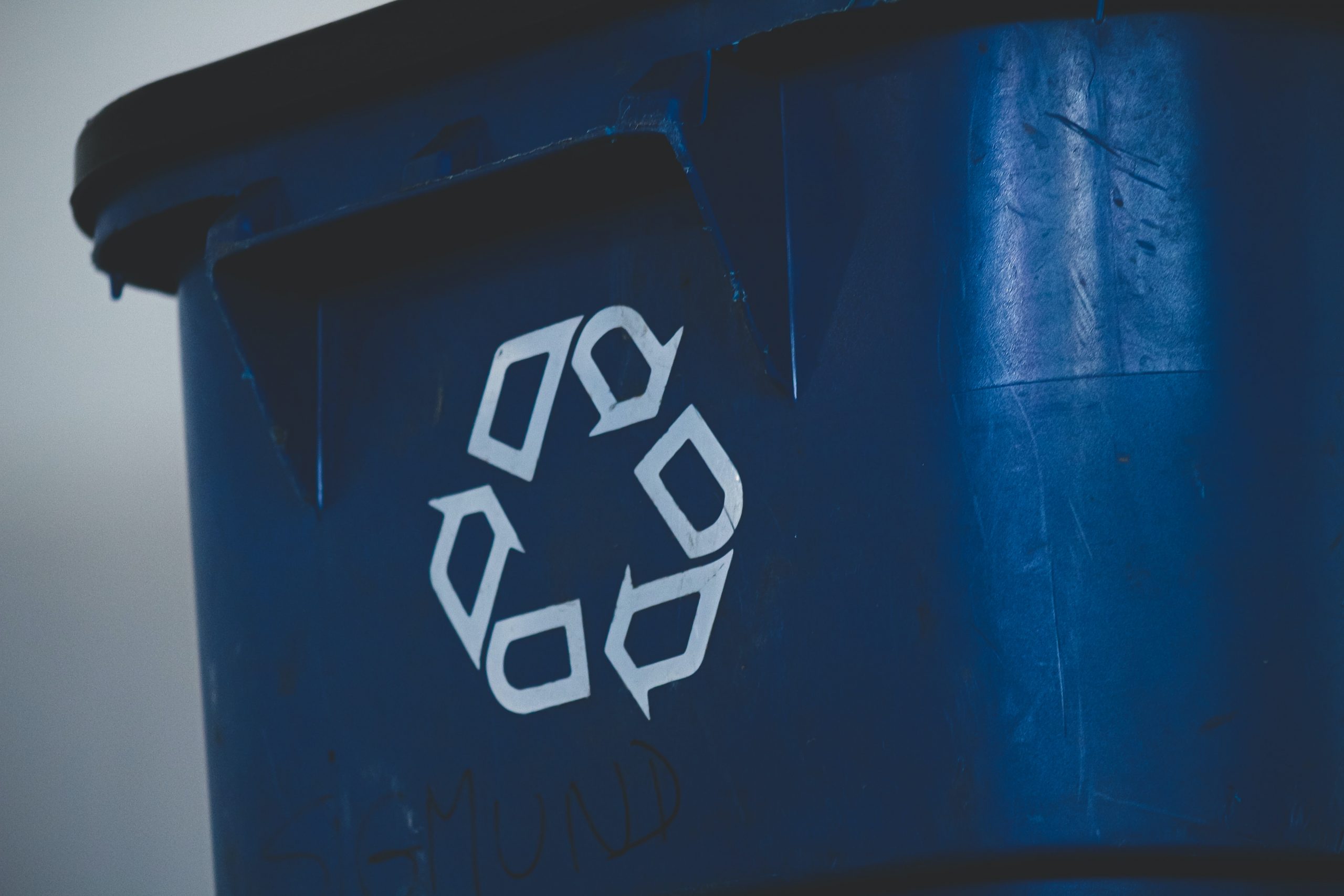 Close up of a blue bin with a recycling symbol painted on in white.