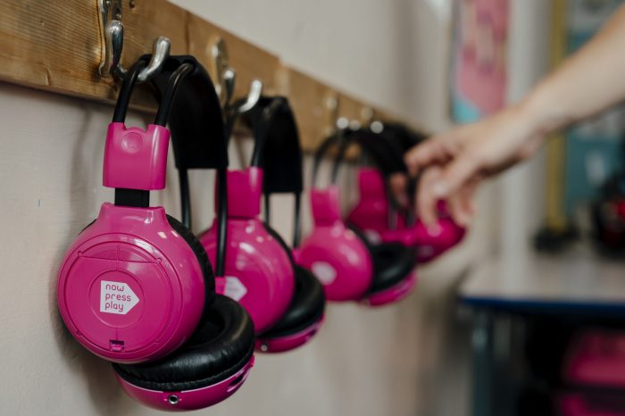 A picture of pairs of Now Press Play headphones hung up in a classroom.