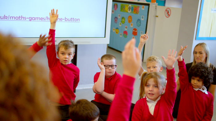 Children in Parklands School's Resource Provision raising their hands to answer a question after taking part in a Now Press Play Experience.