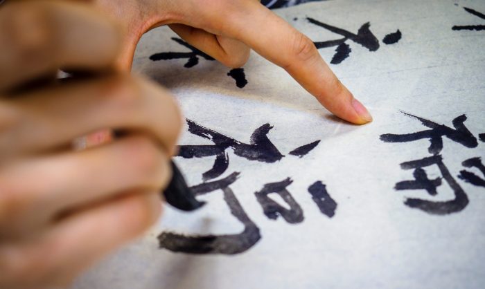 Close-up picture of a person writing Chinese characters on a piece of paper.