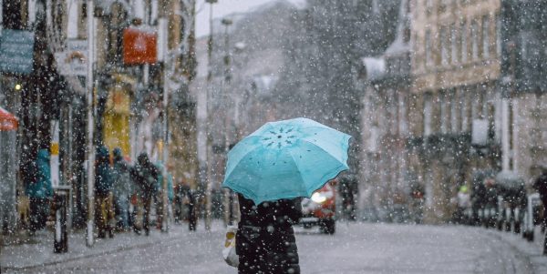 A person with an umbrella walks through a snowy town centre in Britain