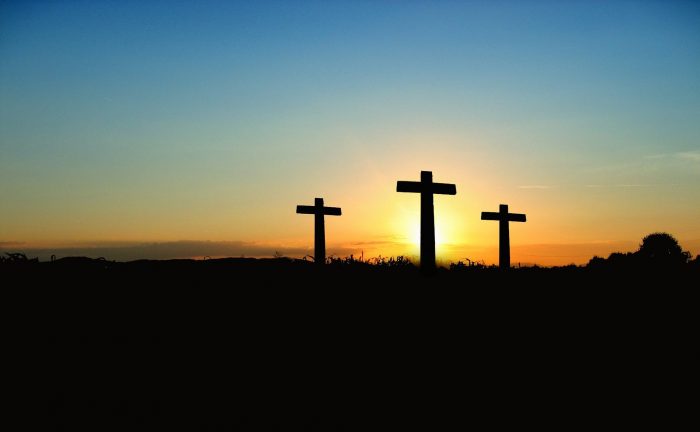 Three Easter crosses silhouetted against a sunset sky.