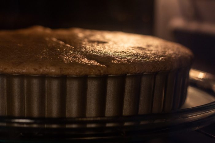 A brown cake baking in an oven.