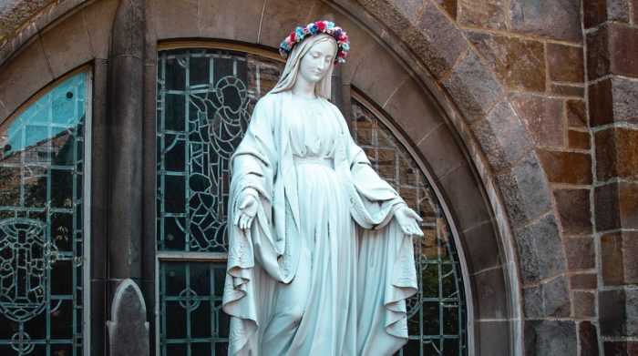 Picture of a statue of the Virgin Mary, with a flower wreath on its head.
