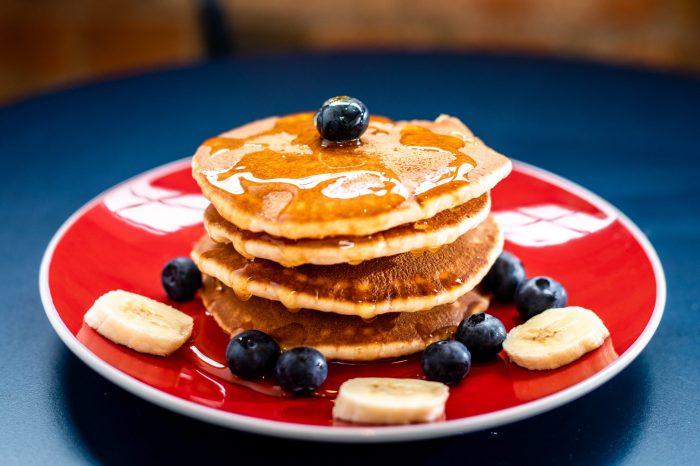 A stack of blueberry pancakes on a red plate.