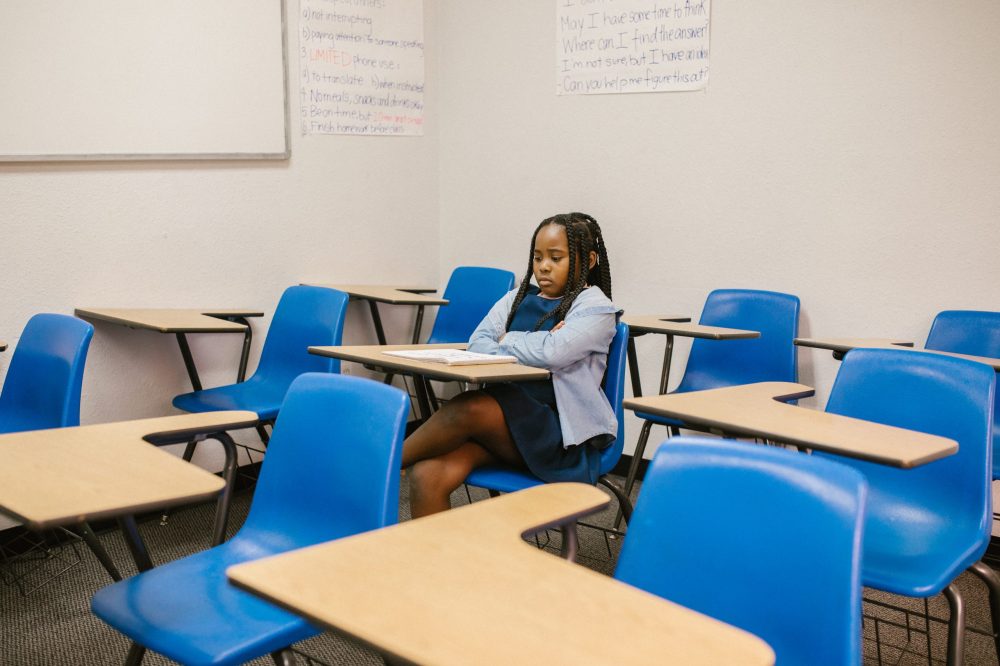 Young girl alone in classroom looking sad