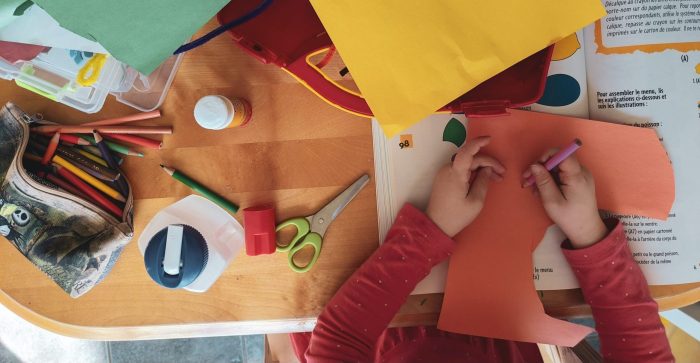 A child makes art using paper, pencils, and other art implements.